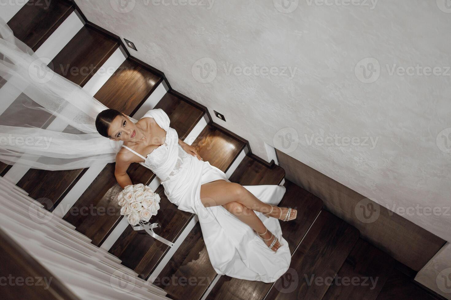 Beautiful bride, fashionable portrait in a stylish interior. Brunette bride, happy woman wearing wedding white dress with wedding makeup and hairstyle. Top photo of the bride. Newlyweds