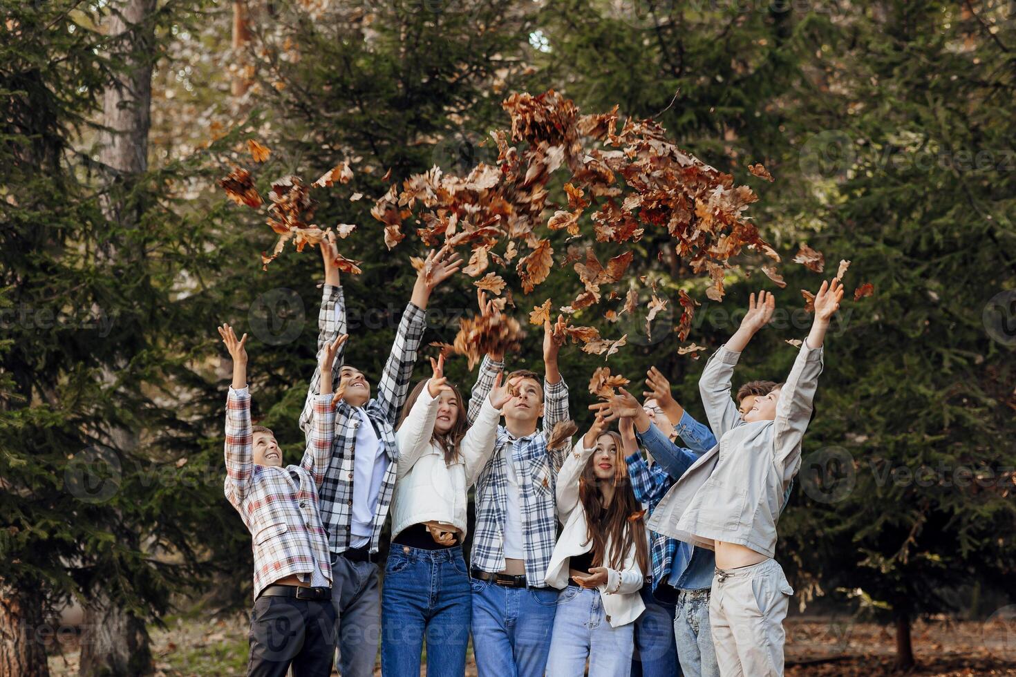 friendship, movement, action, freedom and people concept - group of happy teenagers or school friends posing and having fun outdoors against nature or forest background. photo