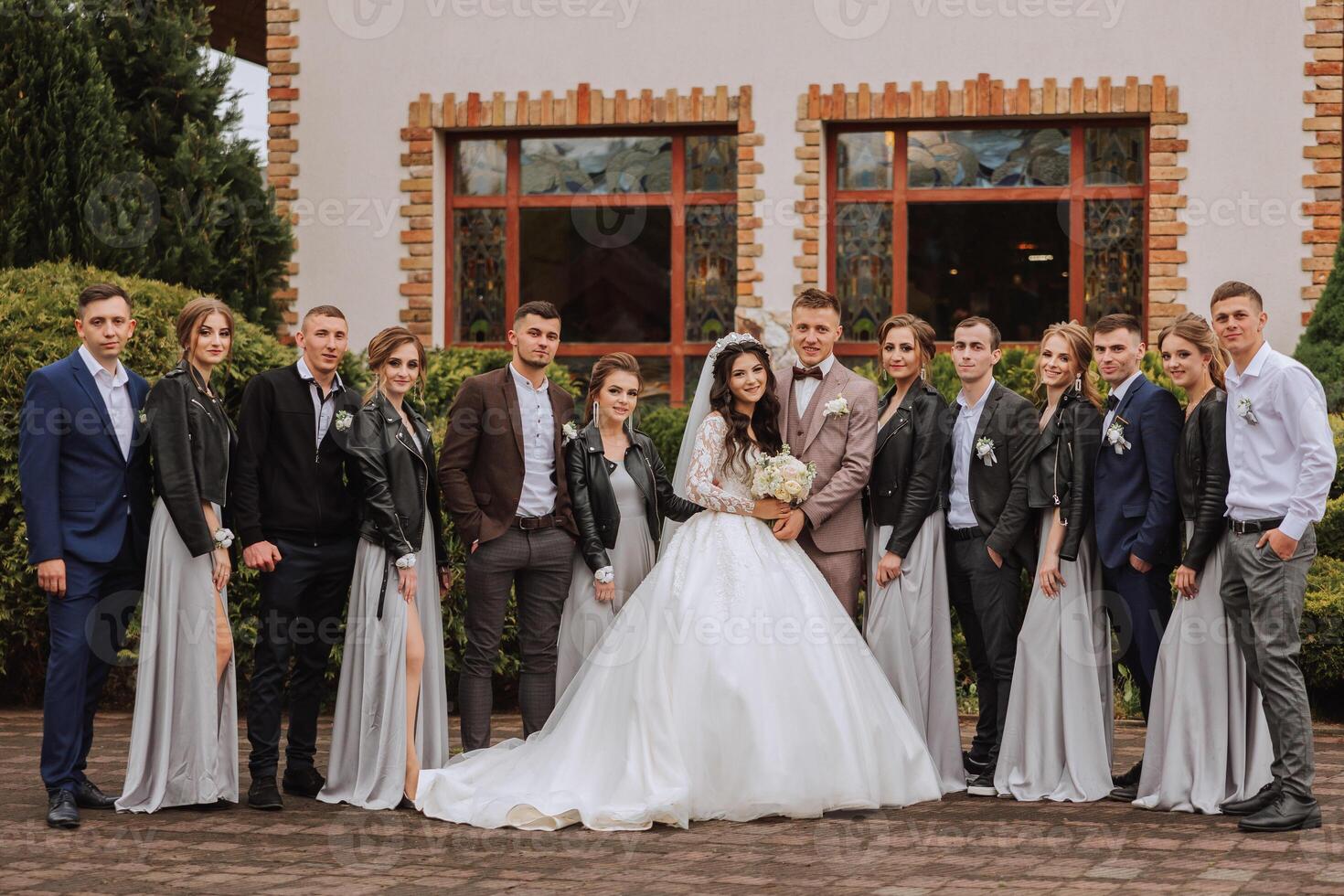 full-length portrait of the newlyweds and their friends at the wedding. The bride and groom with bridesmaids and friends of the groom are having fun and rejoicing at the wedding. photo