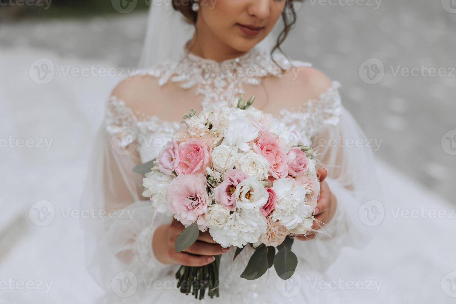 The bride is holding a wedding bouquet. Cropped photo. Details at the wedding. White lace dress photo