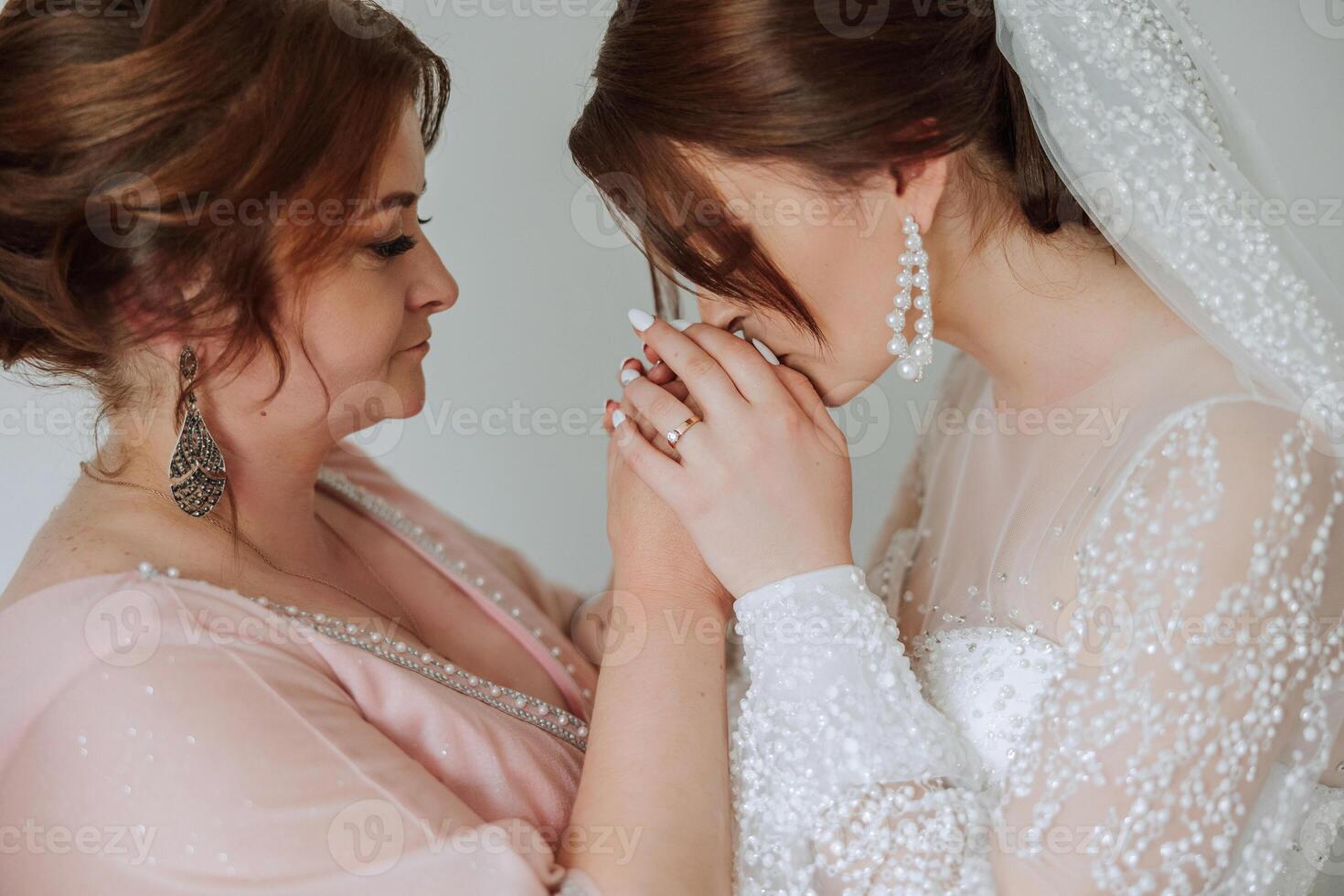 A beautiful and happy mother and her daughter, the bride, are standing next to each other. The best day for parents. Tender moments at the wedding. photo
