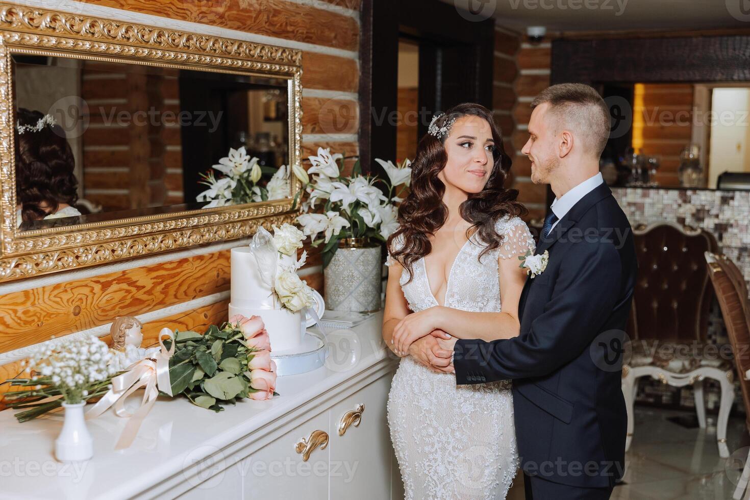 Wedding. Groom and bride near the wedding cake. A sweet and delicious dessert for a wedding. The bride cuts the wedding cake with the help of her lover. The groom embraces his beloved. photo