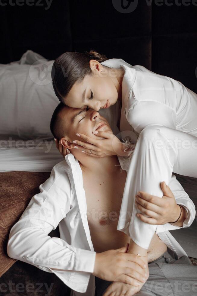 Sensual and tender morning of the bride and groom in the hotel room. Happy and in love brides and grooms. Confident girl bride and handsome groom. Preparation for the wedding photo