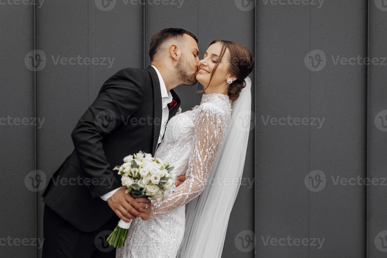 the groom tenderly kisses the bride. Young wedding couple on their wedding photo