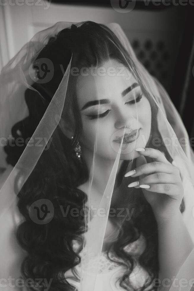 A beautiful brunette bride with a tiara in her hair is getting ready for the wedding in a beautiful robe in boudoir style. Close-up wedding portrait, photo. photo