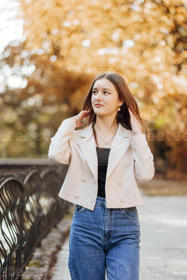 Vertical photo. Beautiful carefree young teenage girl in casual clothes. Portrait of a beautiful girl against the background of nature with a blurred background. photo