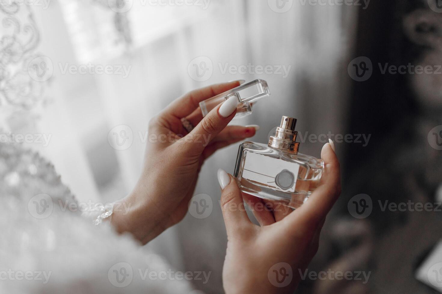 The bride holds perfume. Cropped photo, focus on perfume. Beautiful hands and manicure photo
