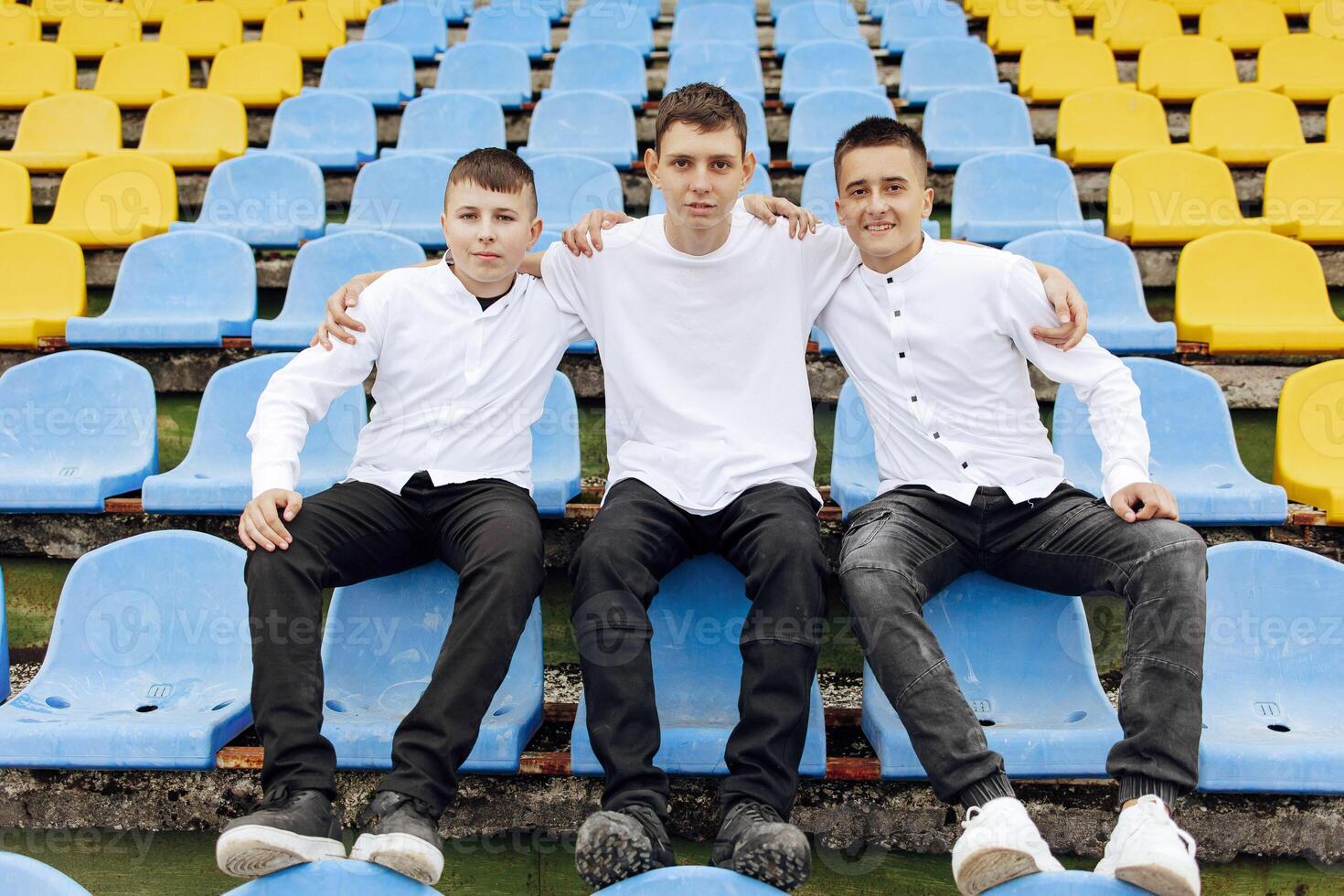 A group of many happy teenagers dressed in the same outfit having fun and posing in a stadium near a college. Concept of friendship, moments of happiness. School friendship photo