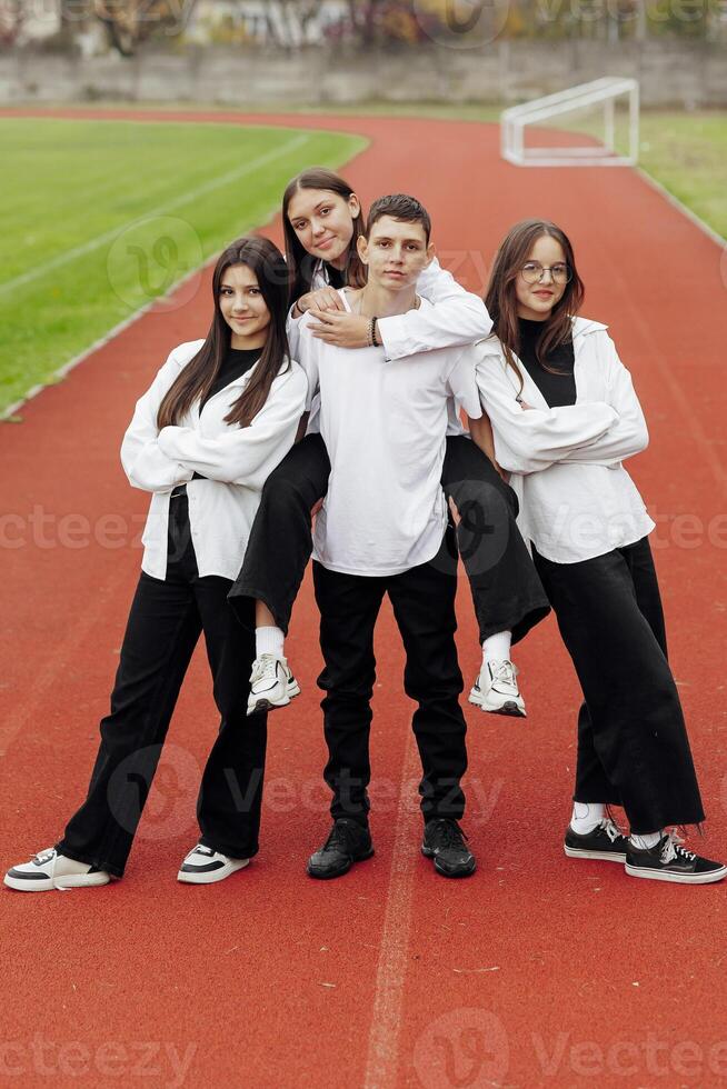 Portrait of four teenage in casual clothes sitting in a stadium and posing looking at the camera. Concept of friendship. A moment of happiness. photo