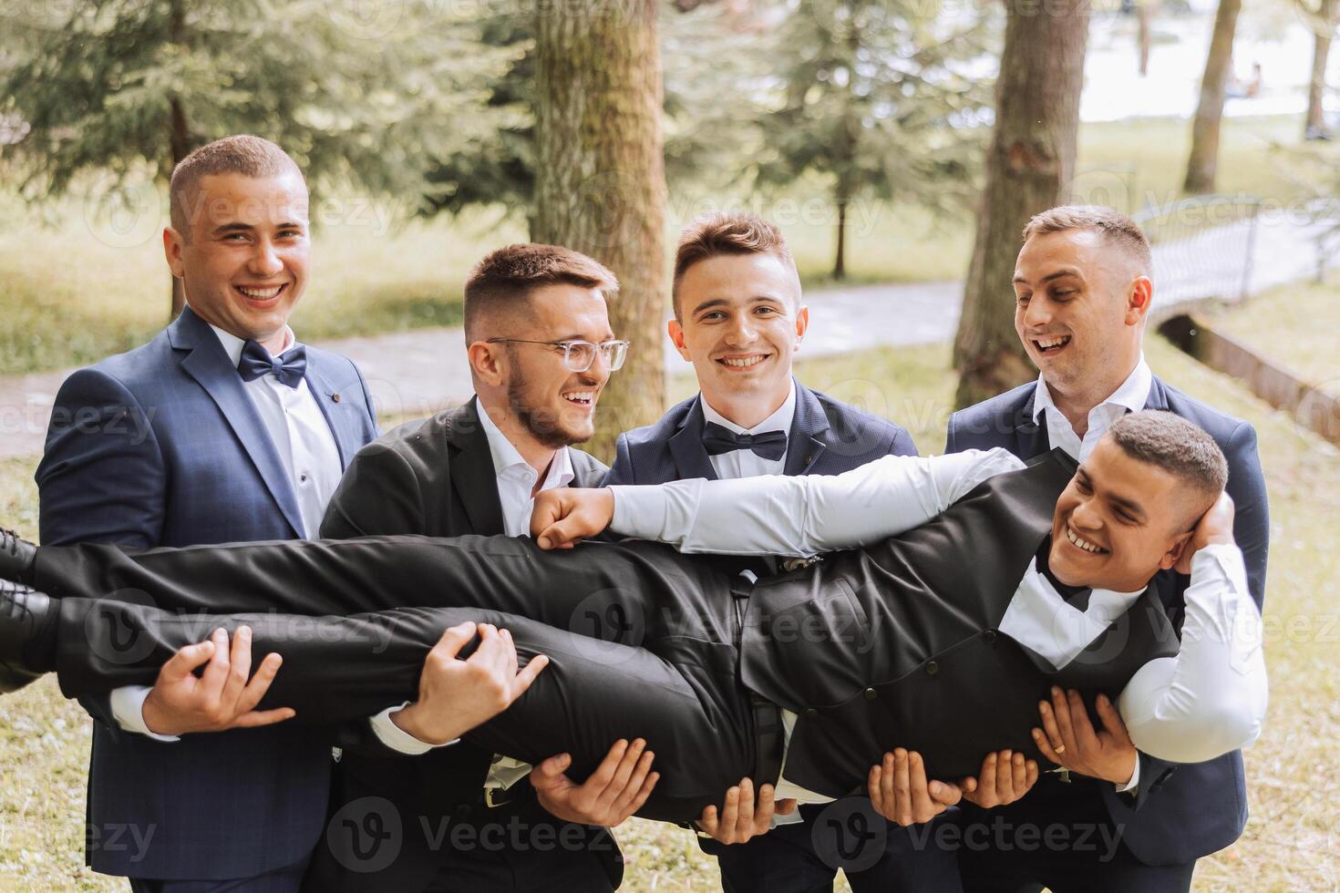 Cheerful, young, energetic witnesses of the groom next to the groom. Friends congratulate the groom. Groom and his funny friends having fun on the wedding day of the newlyweds. photo