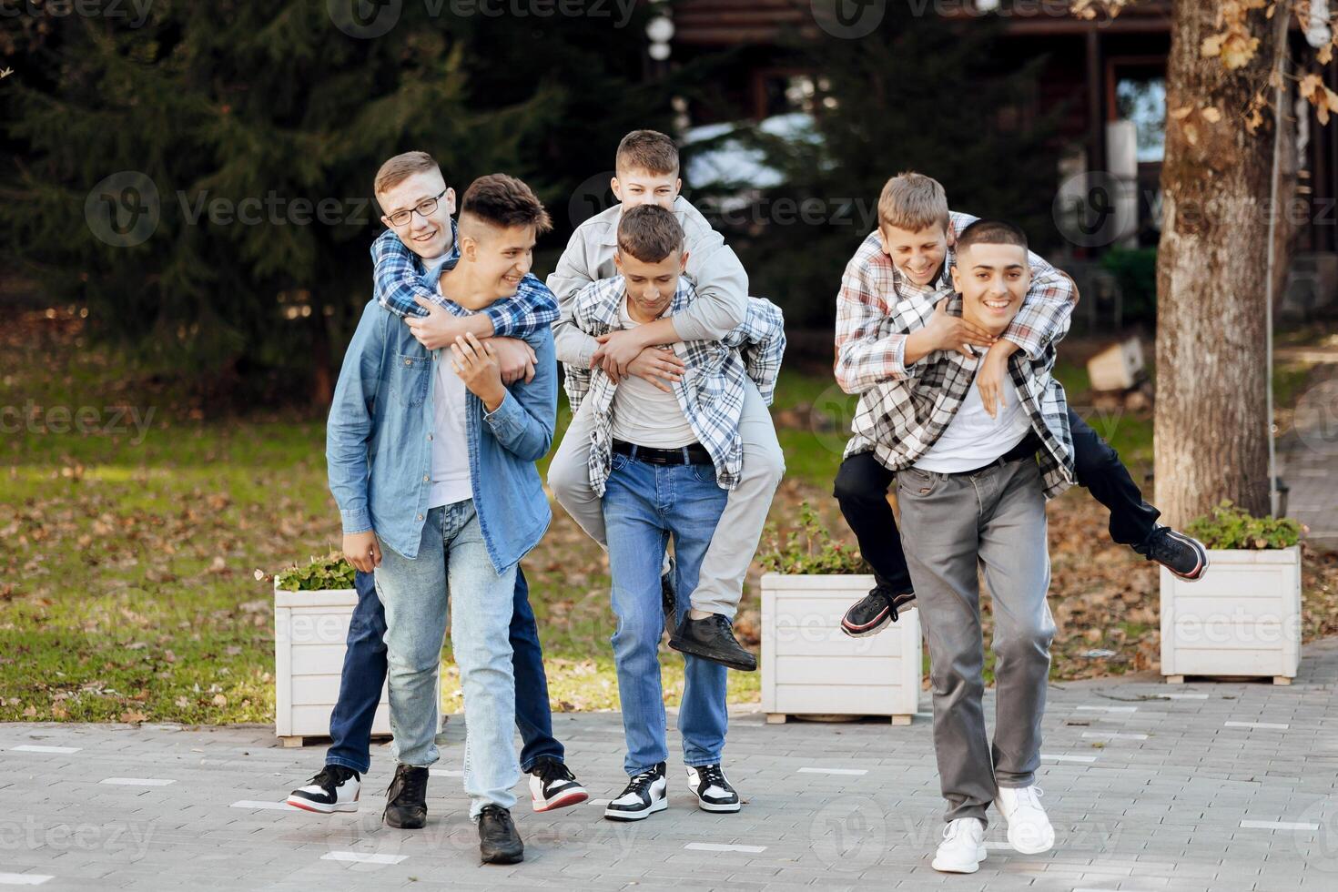 A group of teenagers have fun and rejoice, running in the park. Teenage classmates are resting against the background of autumn nature. photo