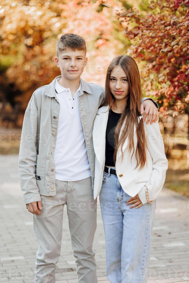 Vertical photo of two teenage friends dressed in casual clothes standing next to each other against a background of nature. Best school friends are ready to overcome anything to achieve the goal.