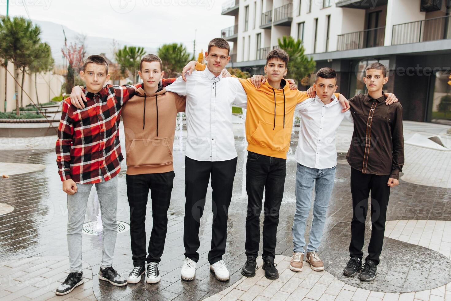 grupo de sonriente y contento Adolescente amigos vistiendo casual ropa gasto hora juntos, posando y hablando con cada otro cerca Universidad edificio en otoño día. foto