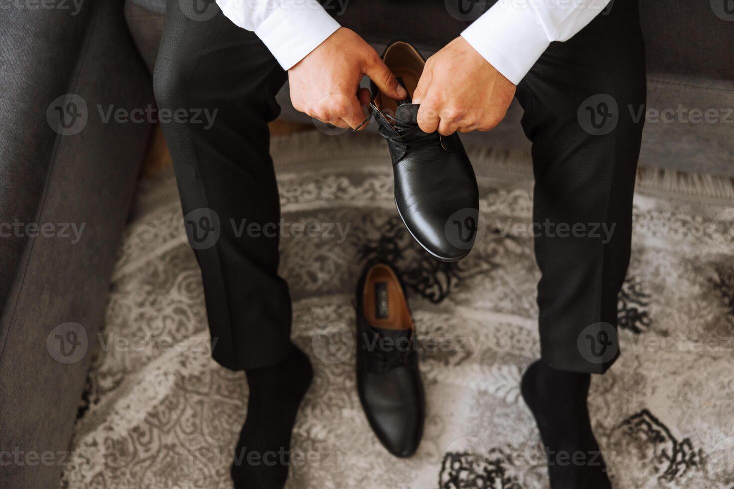 An elegant man wears black leather formal shoes. Tying shoes. Business man tying shoelaces on the floor. Up close The groom is preparing for the wedding. photo