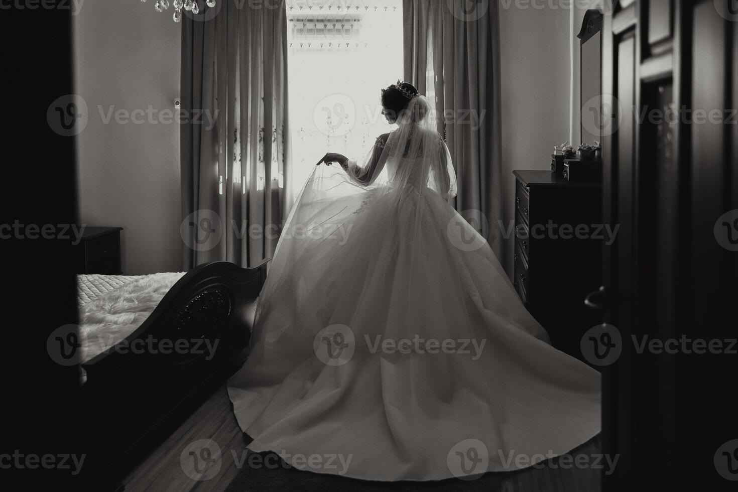 A luxurious bride with a beautiful hairstyle and a gorgeous dress is getting ready for the wedding ceremony in the morning. Morning photo of the bride at home or in a hotel room. Professional makeup.