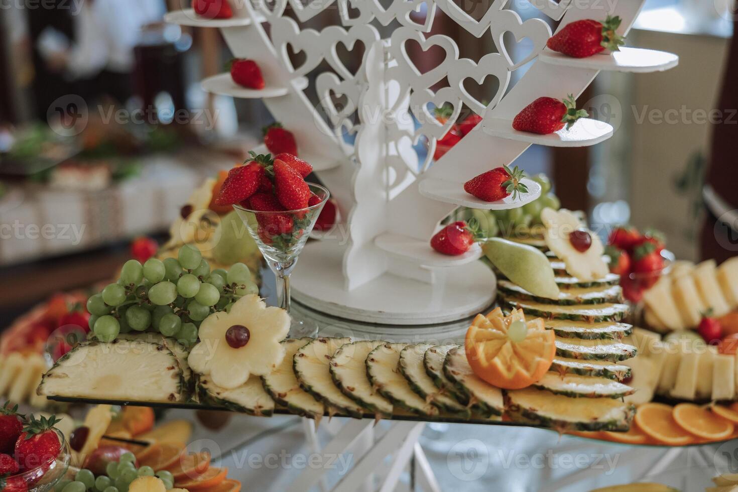 A banquet table full of fruits and berries, an assortment of sweets. Bananas, grapes, pineapples. Fruit compositions for the holiday. photo