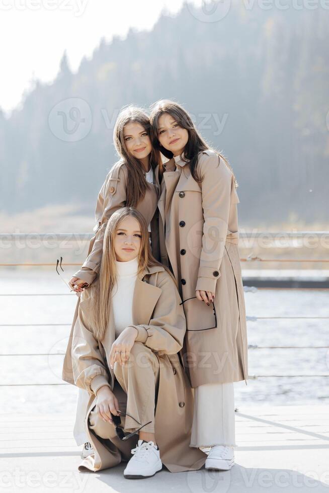 Tres hermosa joven Adolescente muchachas en idéntico ropa posando juntos al aire libre. urbano estilo de vida. ciudad centro. mejor amigos en casual ropa. foto