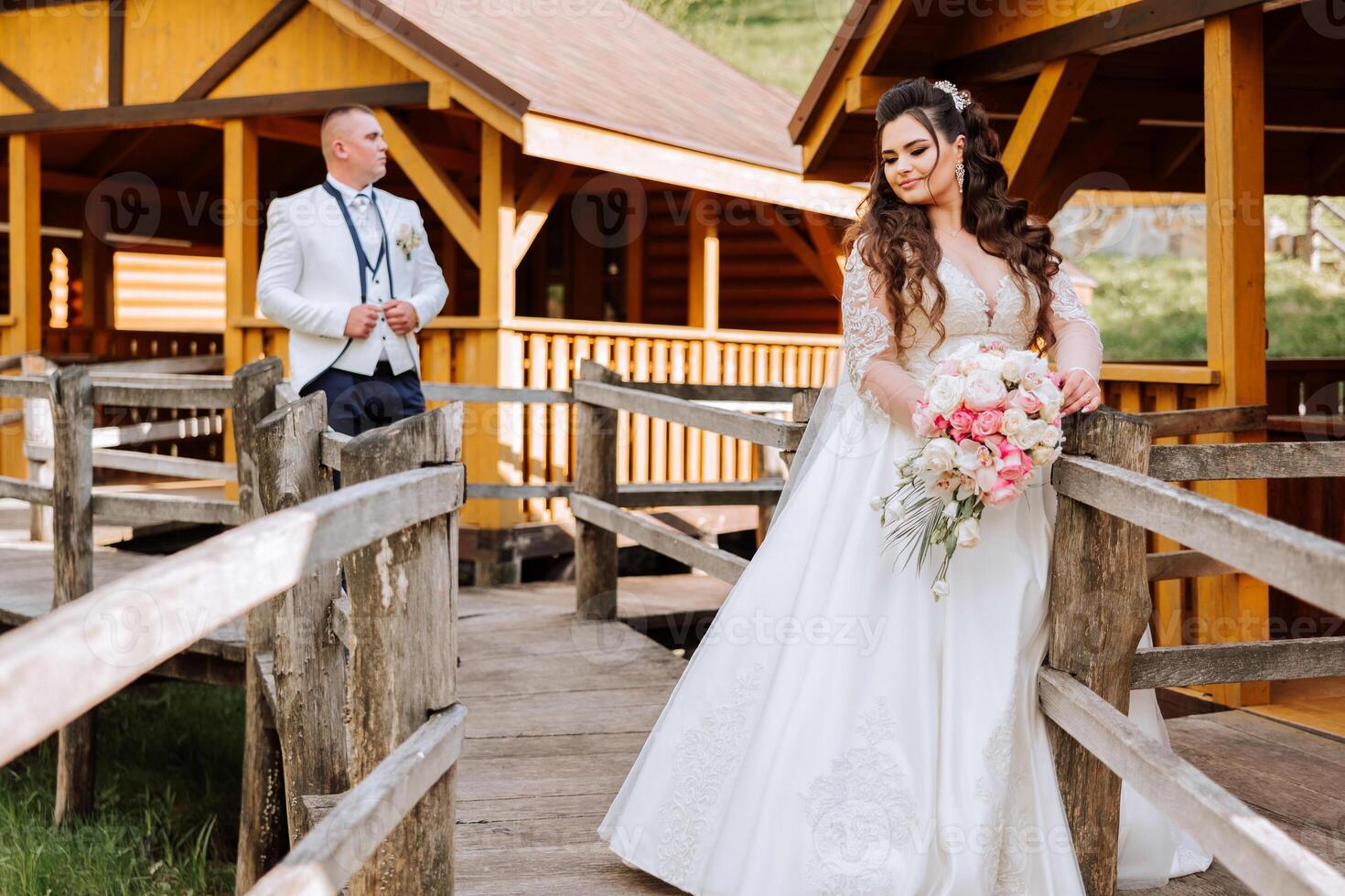 A beautiful young bride, in a summer park, walks ahead of her groom. Beautiful wedding white dress. Walks in the park. A happy and loving couple. photo