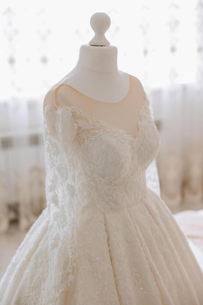 Bedroom interior with wedding dress prepared for the ceremony. A beautiful lush wedding dress on a mannequin in a hotel room. photo