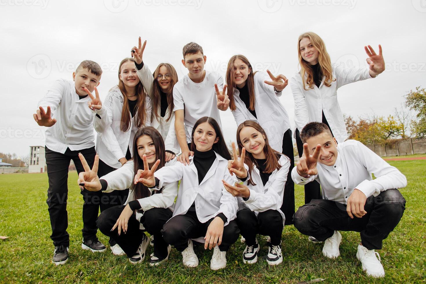 A group of many happy teenagers dressed in the same outfit having fun and posing in a stadium near a college. Concept of friendship, moments of happiness. School friendship photo