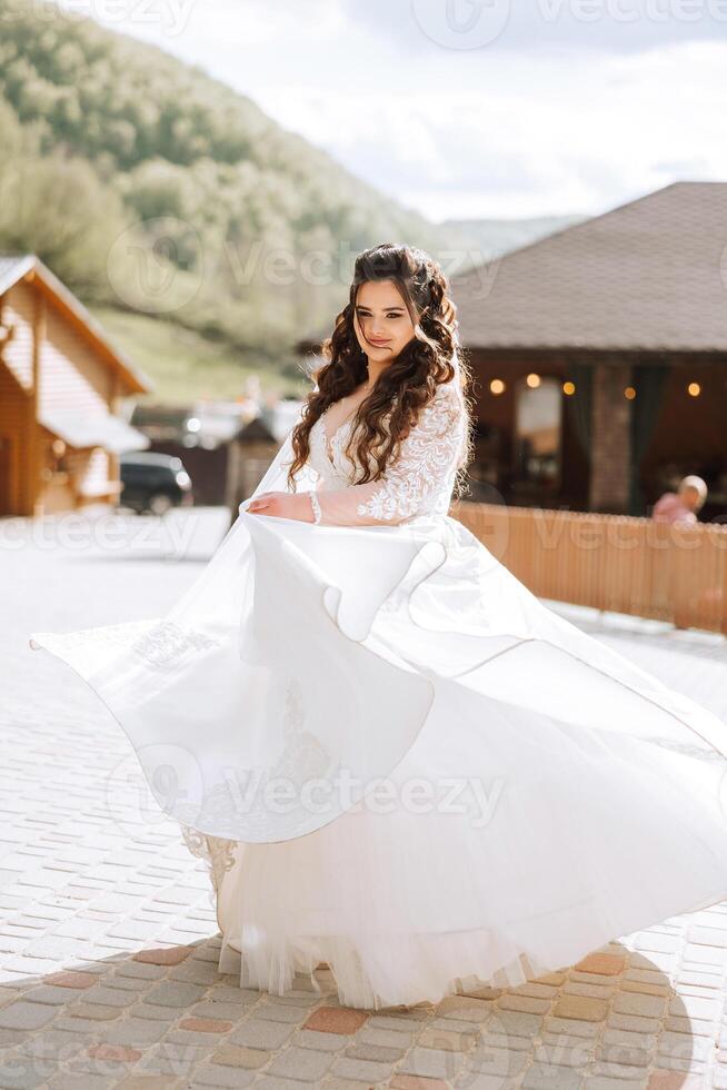 Rizado novia giros en su Boda vestido. magnífico vestir con largo mangas, abierto busto. verano Boda foto