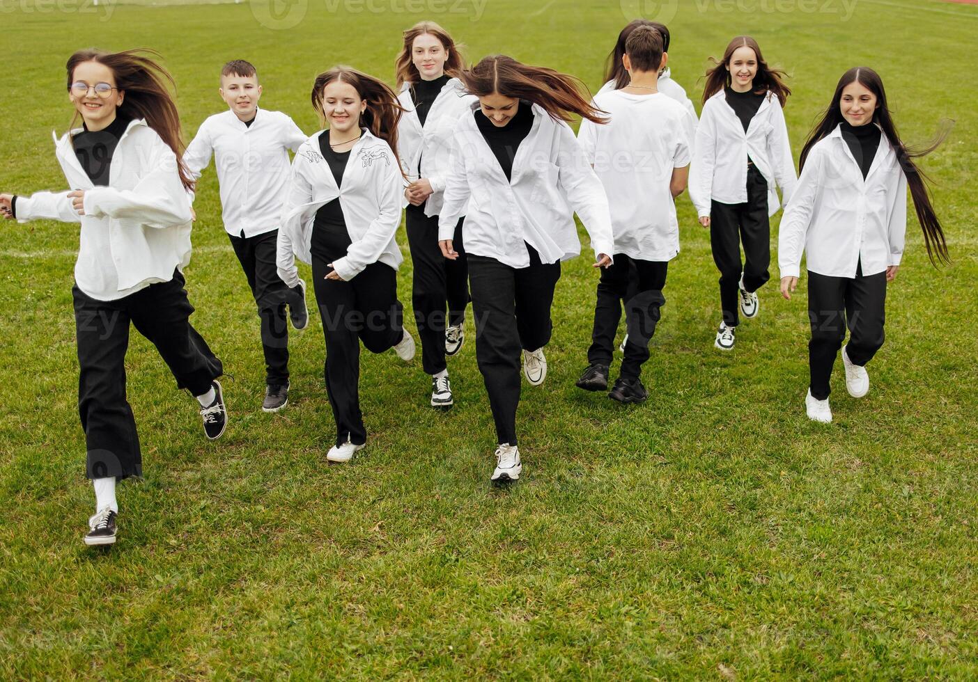 A group of many happy teenagers dressed in the same outfit having fun and posing in a stadium near a college. Concept of friendship, moments of happiness. School friendship photo