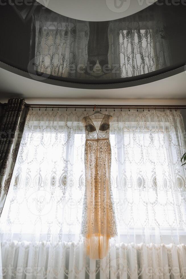 Bedroom interior with wedding dress prepared for the ceremony. A beautiful lush wedding dress on a mannequin in a hotel room. photo