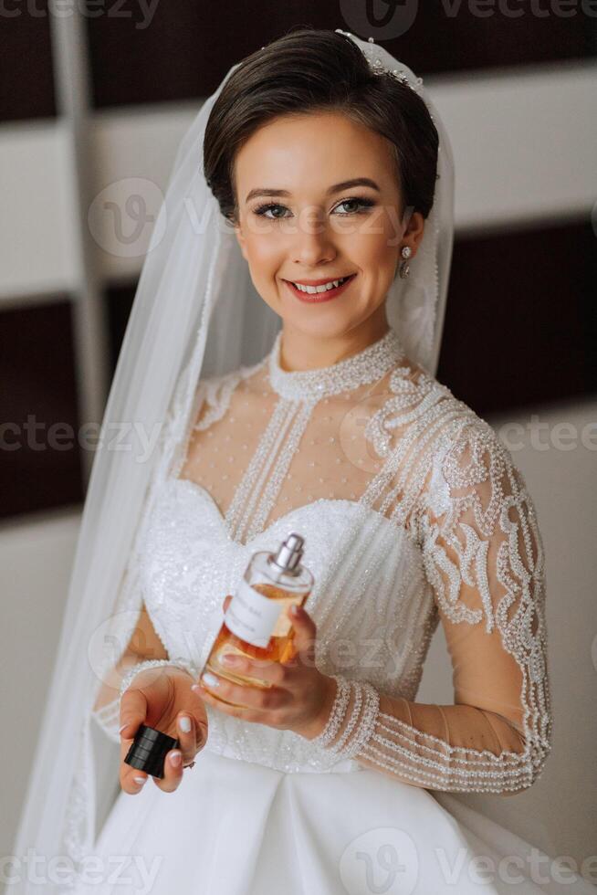 un novia en un elegante vestir con largo mangas participación un botella de lujoso perfume foto