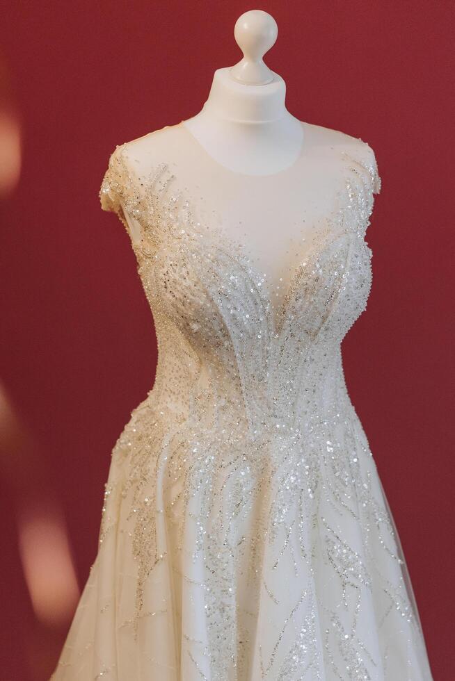 Bedroom interior with wedding dress prepared for the ceremony. A beautiful lush wedding dress on a mannequin in a hotel room. photo
