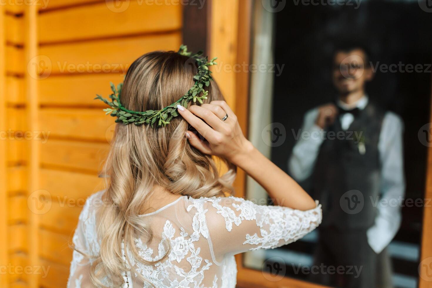 the first meeting of the bride and groom. He looks at her. Bride's hairstyle, back view, wreath of greenery on the bride's head photo