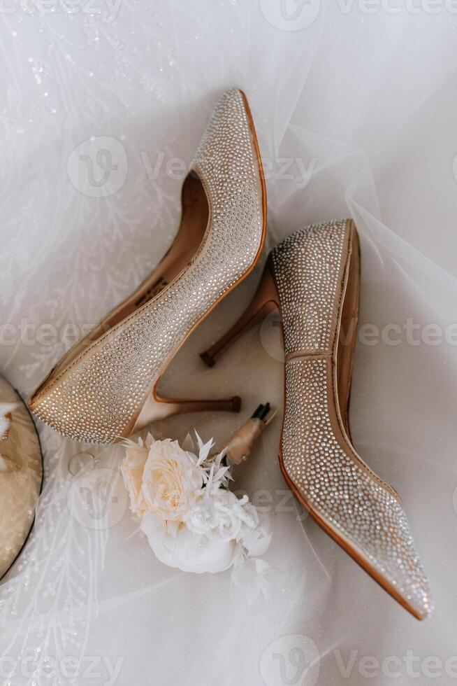 The bride's engagement ring, fashionable stilettos, fresh rose flowers. Wedding details in golden style. photo