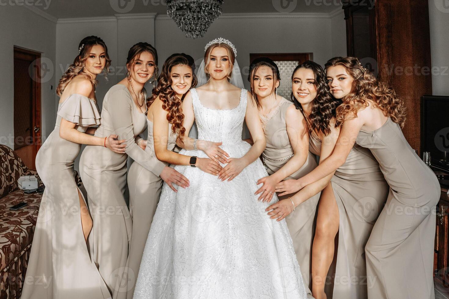 The bride in a white dress, veil and girlfriends in cream dresses, posing in beautiful lighting. Morning of the bride photo