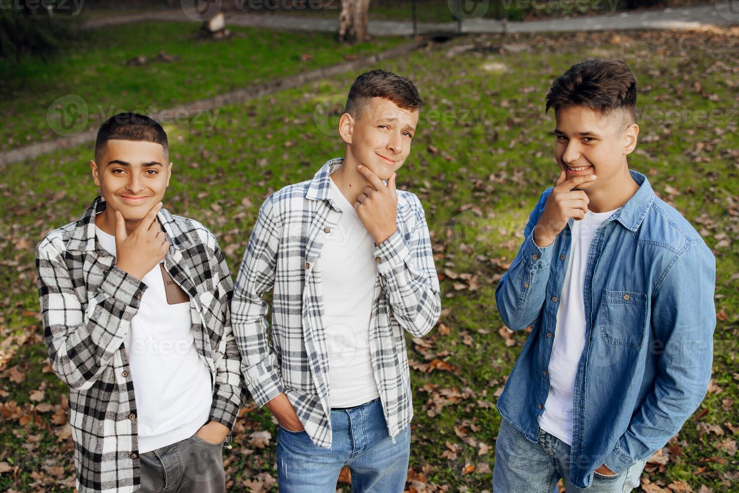 Three teenage boys, posing in nature, rejoicing, running and having fun. Teenage classmates are resting against the background of an autumn forest. photo