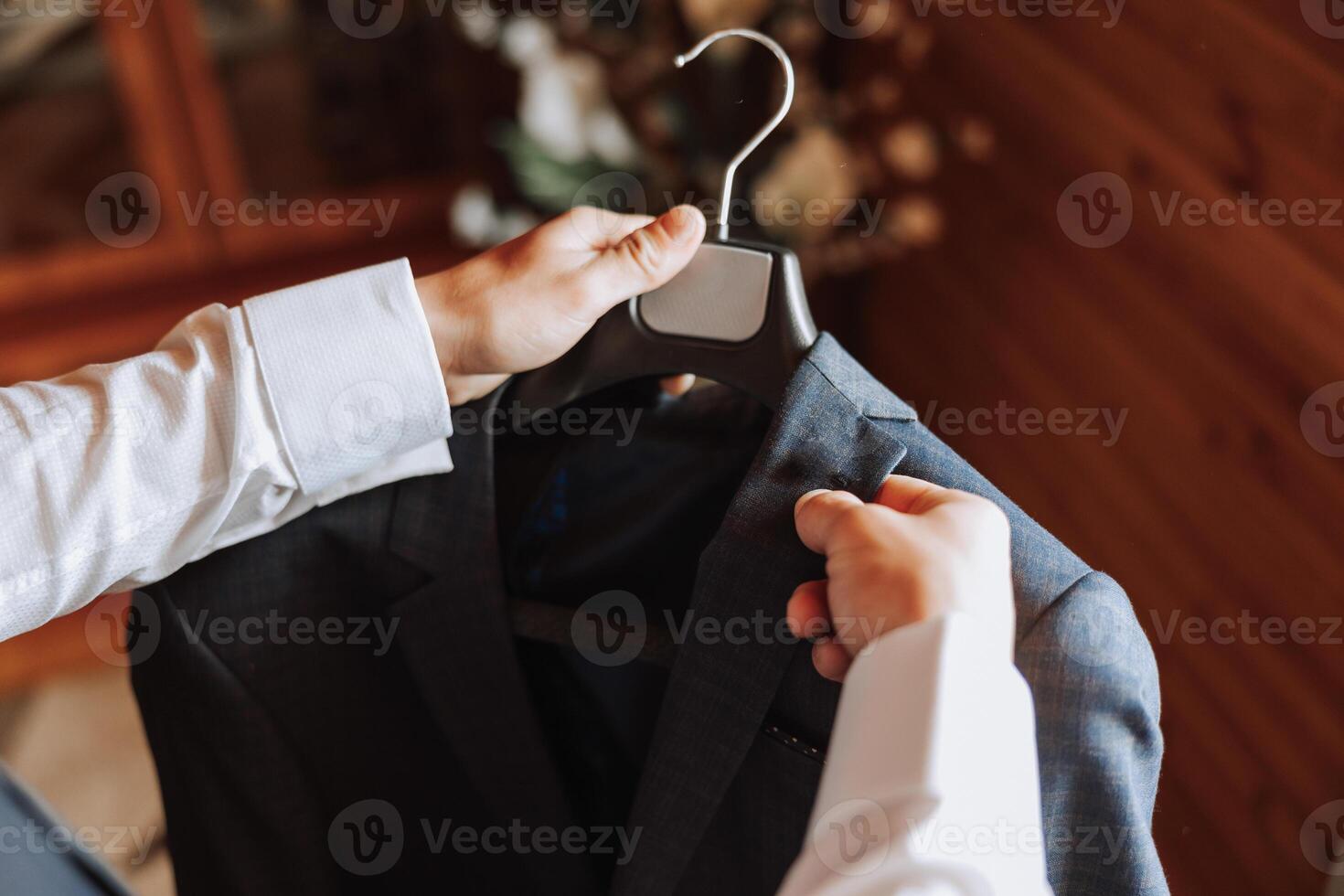 the man holds his black jacket on a hanger in his hands. The groom is preparing for the wedding ceremony. Detailed close-up photo of hands