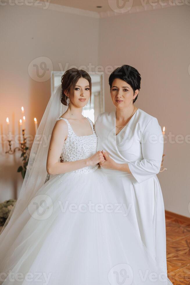 A beautiful and happy mother and her daughter, the bride, are standing next to each other. The best day for parents. Tender moments at the wedding. photo