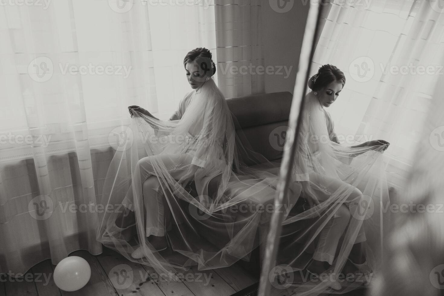 portrait of a luxurious bride in boudoir style near a mirror with reflection. Preparing the bride for the wedding in the morning in a white robe. photo