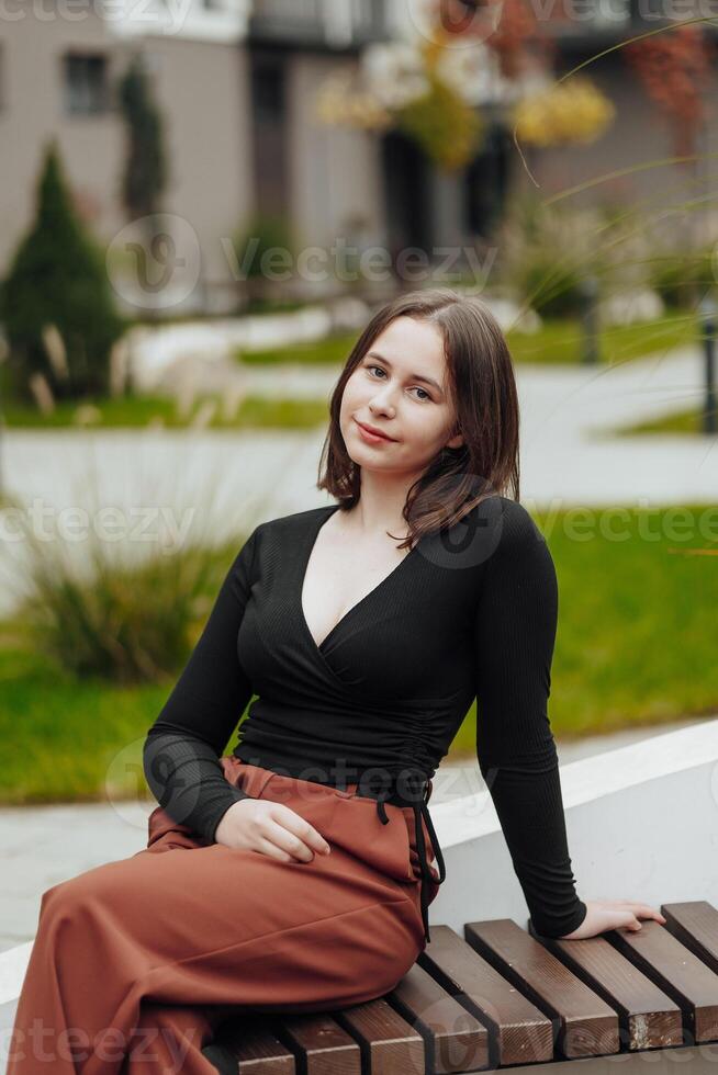 Vertical photo. Beautiful carefree young teenage girl in casual clothes. Portrait of a beautiful girl against the background of nature with a blurred background. photo