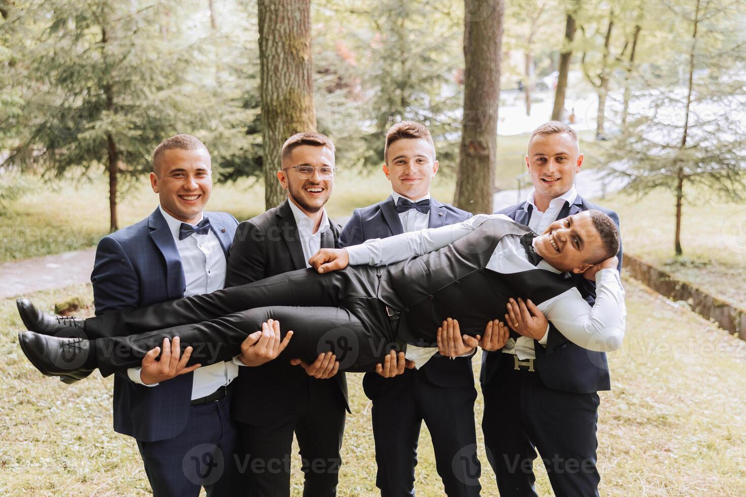 Cheerful, young, energetic witnesses of the groom next to the groom. Friends congratulate the groom. Groom and his funny friends having fun on the wedding day of the newlyweds. photo