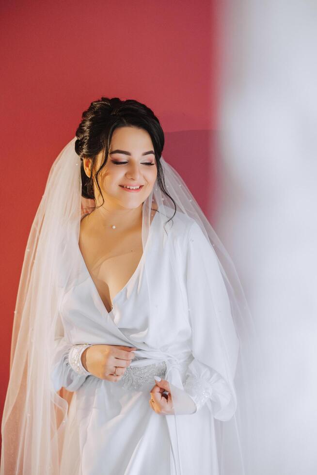 A beautiful brunette bride with a tiara in her hair is getting ready for the wedding in a beautiful robe in boudoir style. Close-up wedding portrait, photo. photo