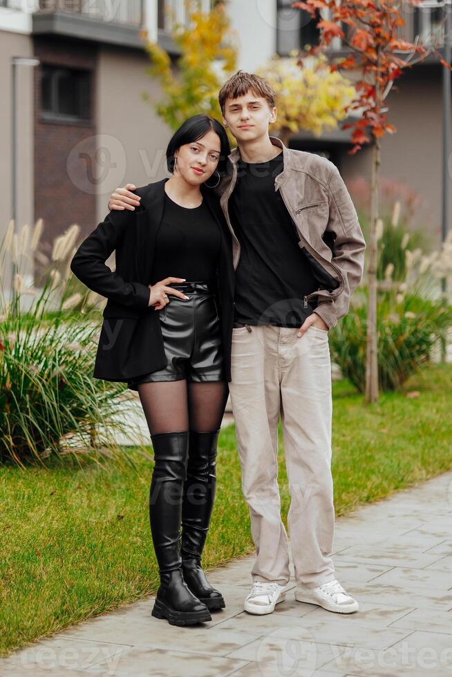 Vertical photo of two teenage friends dressed in casual clothes standing next to each other against a background of nature. Best school friends are ready to overcome anything to achieve the goal.