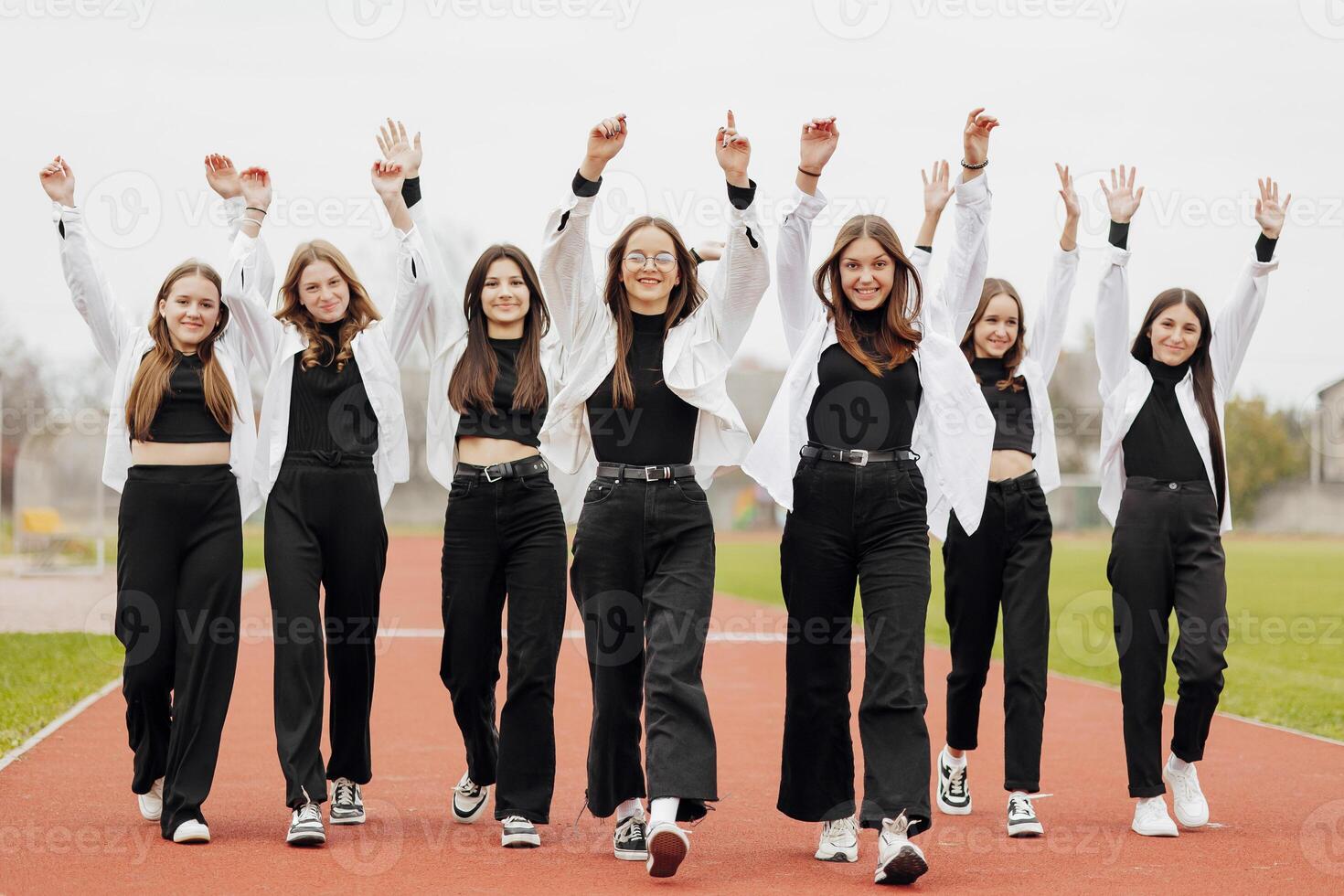 un grupo de muchos contento Adolescente muchachas vestido en el mismo atuendo teniendo divertido y posando en un estadio cerca un colega. concepto de amistad, momentos de felicidad. colegio amistad foto