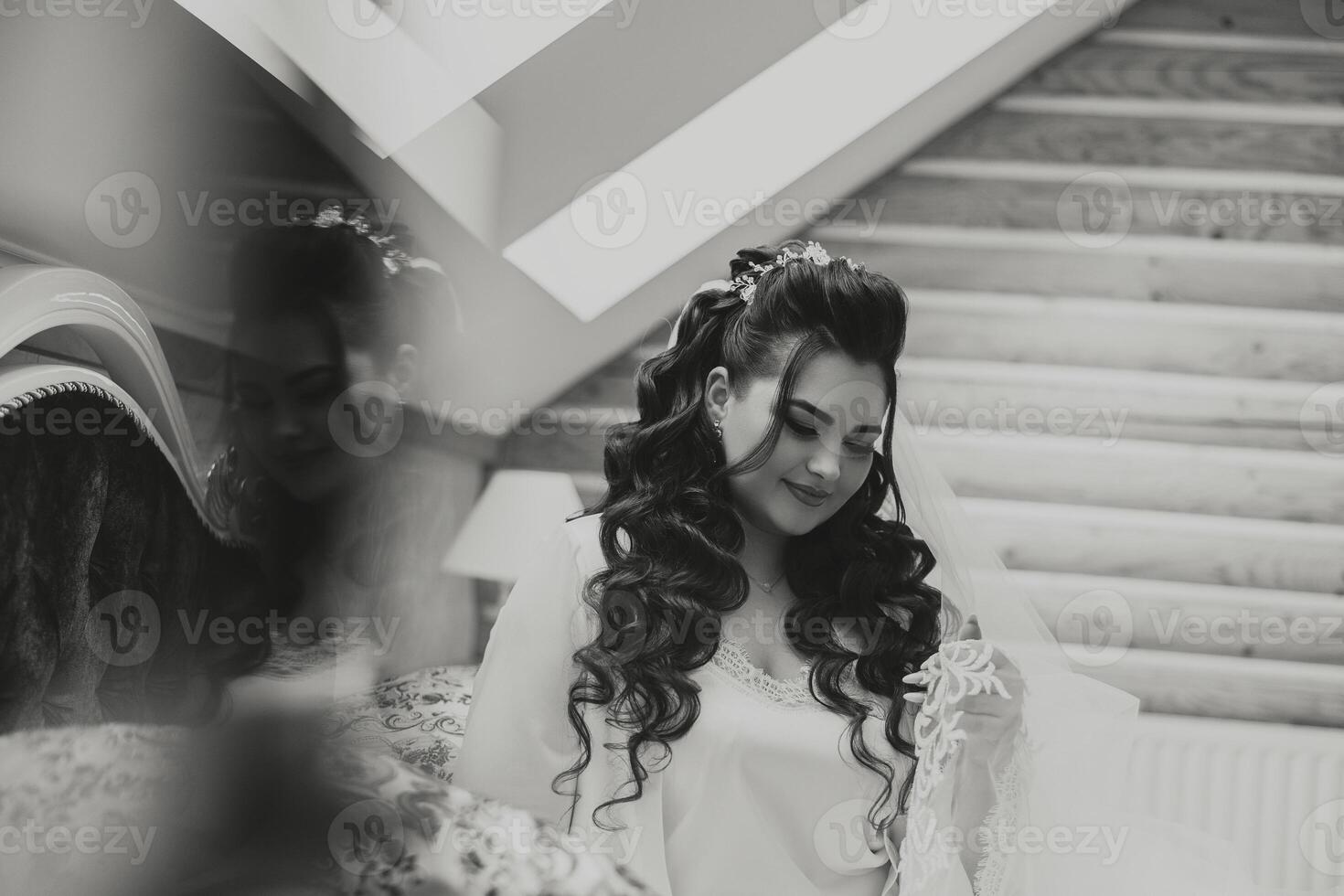 portrait of a luxurious bride in boudoir style near a mirror with reflection. Preparing the bride for the wedding in the morning in a white robe. photo
