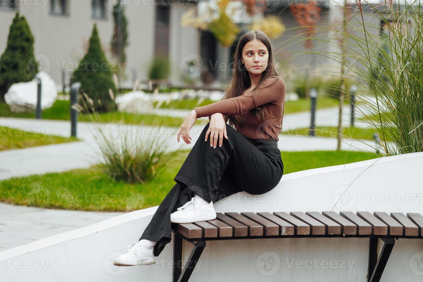 Vertical photo. Beautiful carefree young teenage girl in casual clothes. Portrait of a beautiful girl against the background of nature with a blurred background. photo