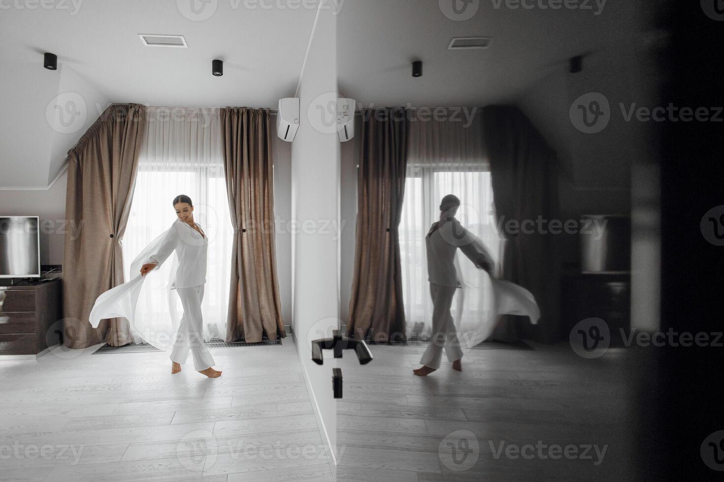 young beautiful bride in white pajamas in the morning. The bride's morning at the hotel. Long fashionable veil. Mirror photo