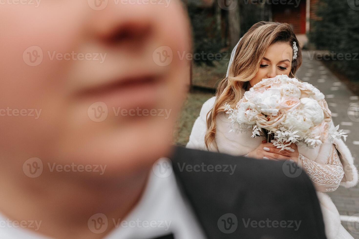 The bride and groom are walking near the hotel and posing, happy and enjoying the day, holding hands. A long train on the dress. Winter wedding photo