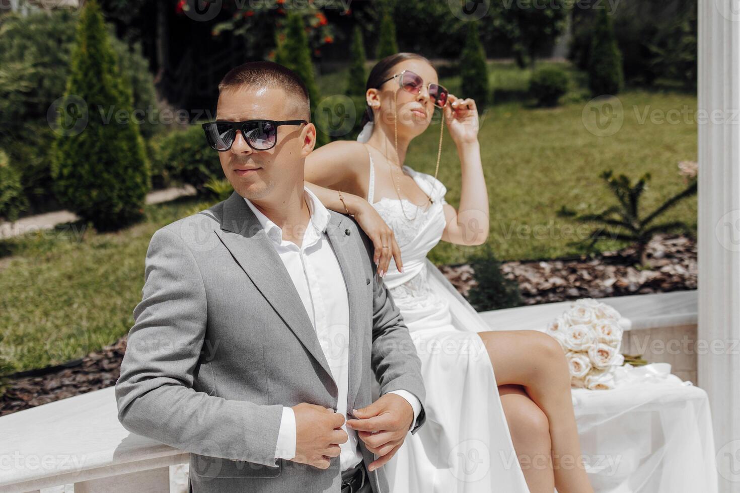 Cool bride and groom having fun and wearing sunglasses outdoors in sunny weather photo