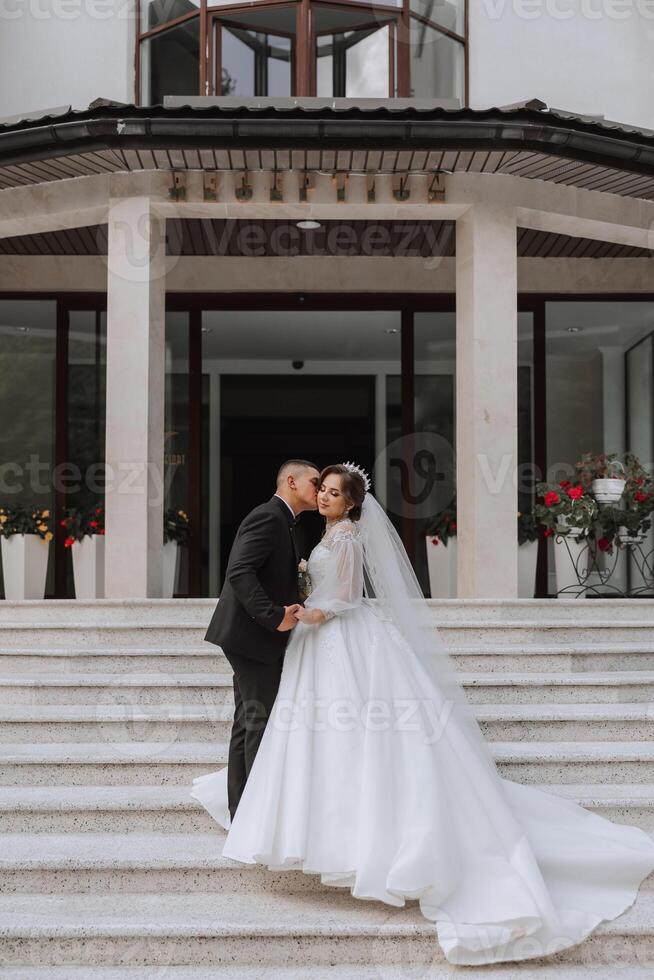 portrait of the newlyweds in classic wedding clothes on a large beautiful staircase. the concept of stores and sales of goods for the bride and groom. photo