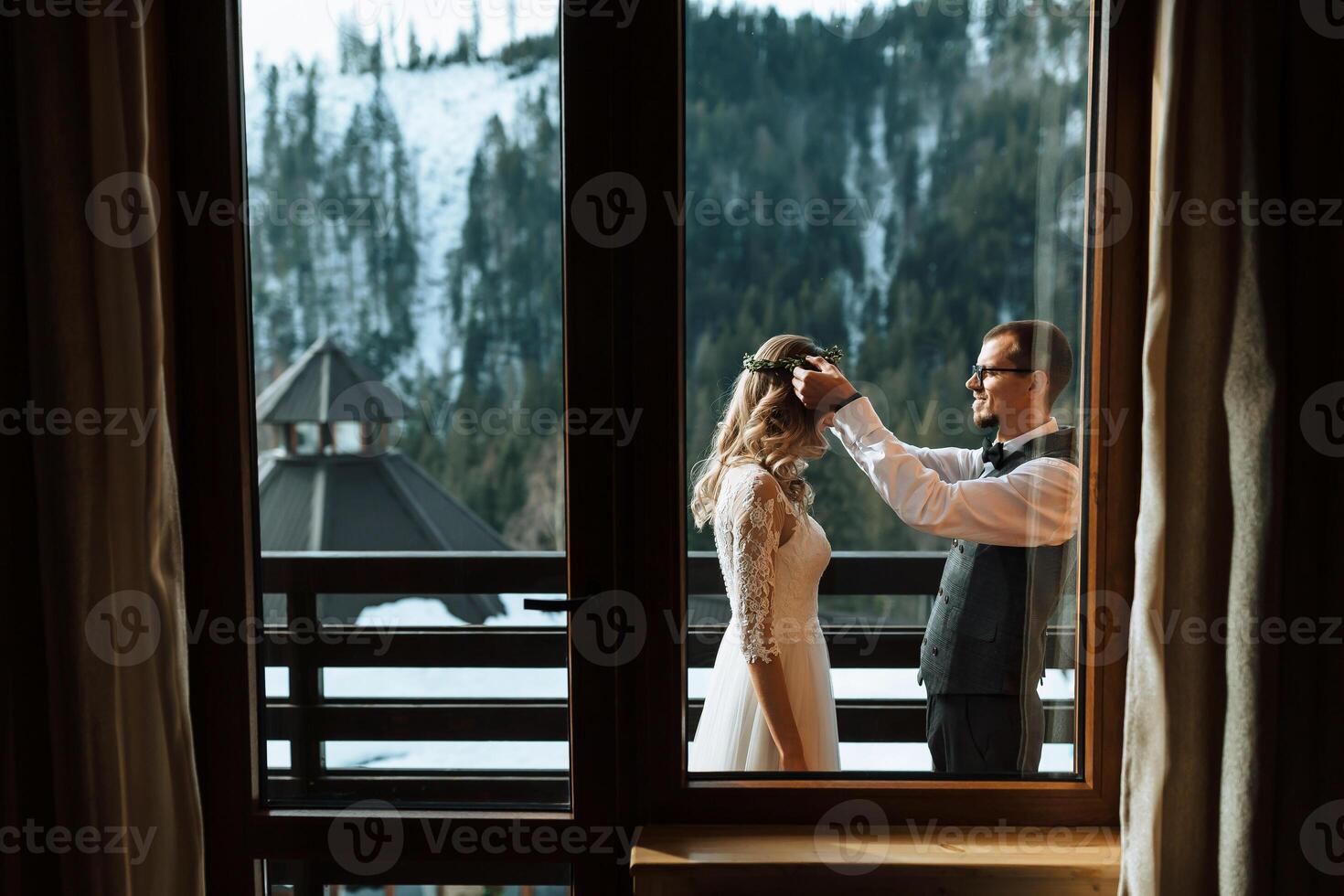 the groom puts a wreath on the bride against the background of snow-capped mountains. A wedding couple is celebrating a wedding in the mountains in winter. photo
