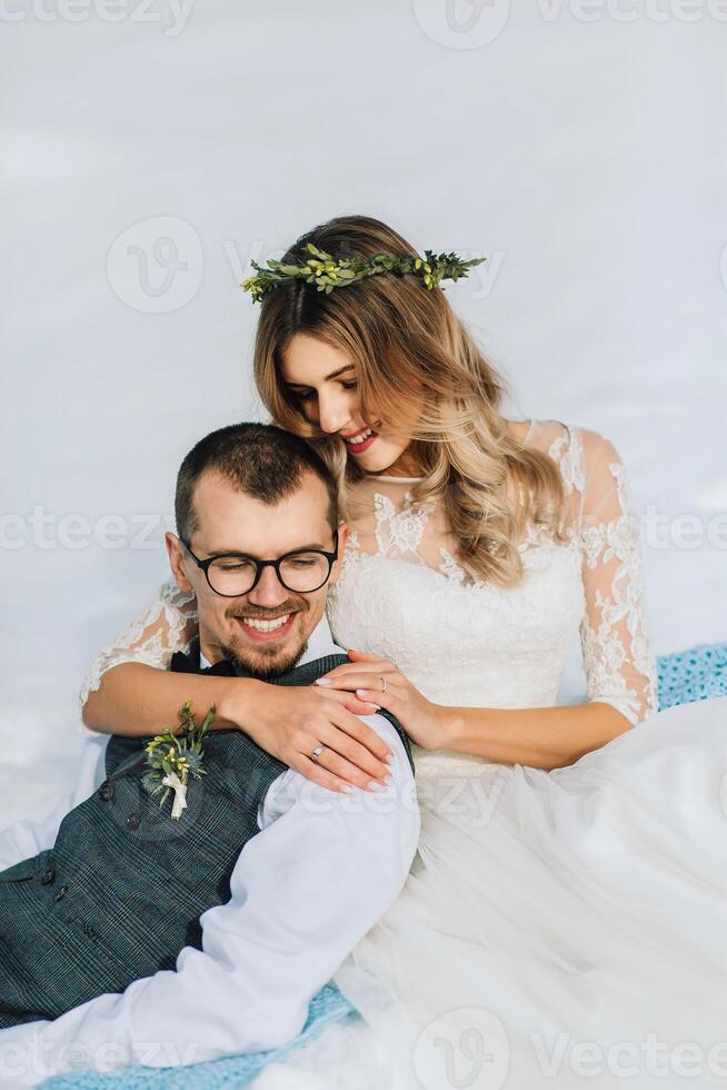 joven hombre y mujer corriendo acostado en nieve, reír, engañando alrededor, teniendo divertido jugando bolas de nieve europeo invierno boda. retrato de el novia y novio en el nieve foto