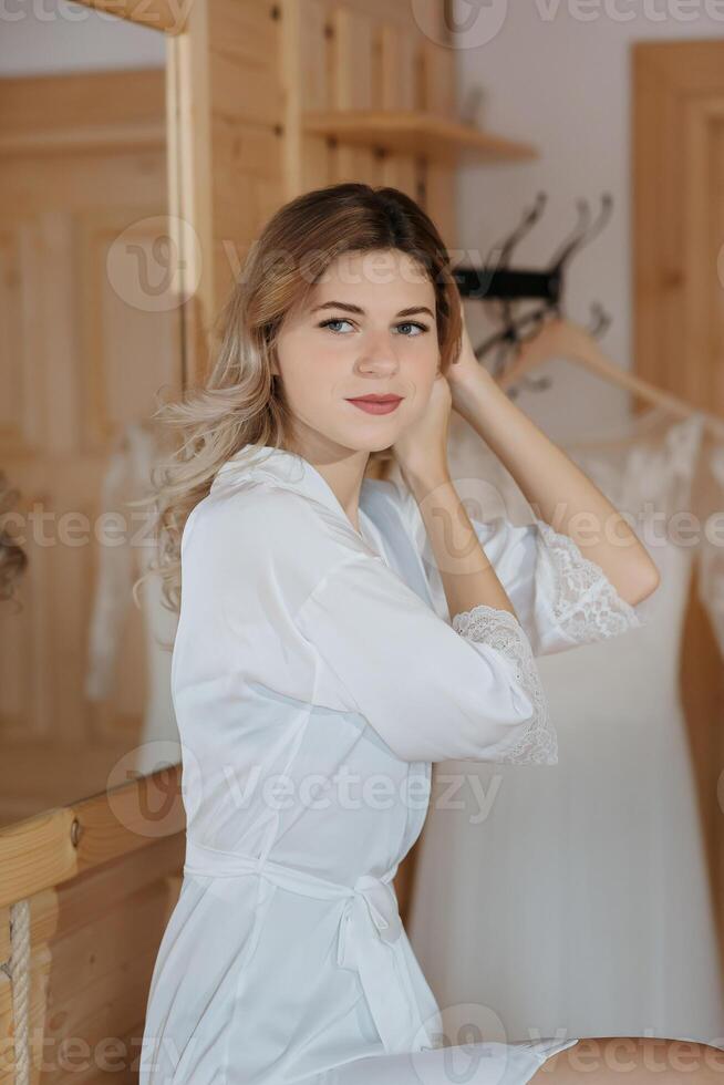 Portrait of white-haired girl at home in living room or bedroom looking into camera lens. A girl in pajamas. Dreamy bride in pajamas in the morning. Close-up portrait photo